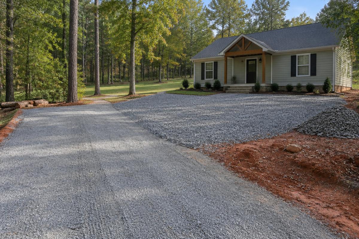 Gravel driveway and parking area with a small stockpile of aggregate beside a home